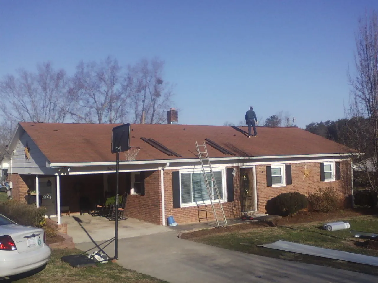 Roofer stripping a shingle roof on a brick ranch before metal panels in Memphis